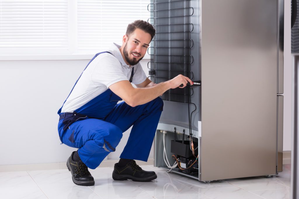 Technician repairing a refrigerator in a Tucson home